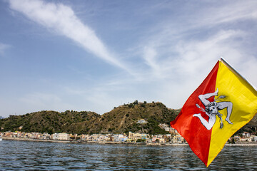 The Sicilian flag and Giardini Naxos in the background