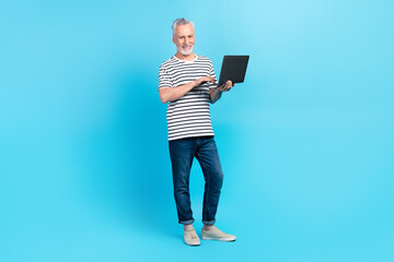 Photo of cheerful man pensioner feel young use hold netbook macbook writing sms isolated on blue...