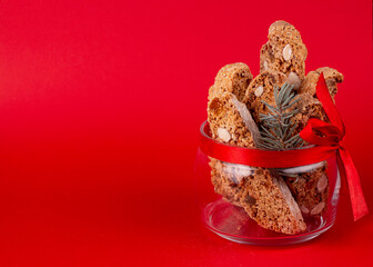 Traditional italian Christmas New Year dry cookies biscuits biscotti cantuccini in glass bowl on red background. Biscotti di Prato. copy space