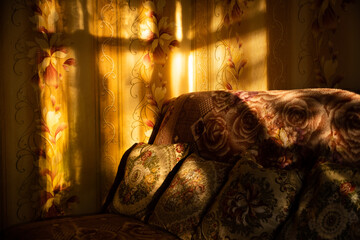 The shadow of the window on the wall with wallpaper on the background of a sofa with pillows
