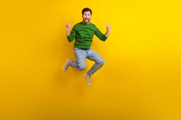 Fototapeta na wymiar Full size body photo of jump trampoline crazy guy fingers showing rock roll punk gesturing singing isolated on yellow color background