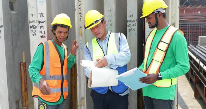 construction blueprint paper. Asian indian construction architect Engineering man and senior worker in safety hardhat working on blue print at Prefabricated concrete factory Heavy industrial