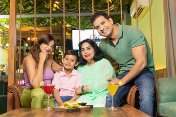 Indian family giving happy expression at restaurant.