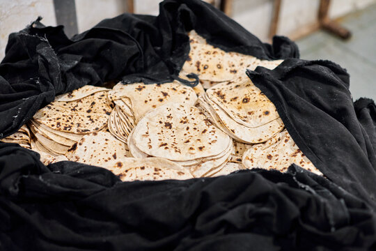 Batch of chapati round flatbreads in black bag for langar in sikh gurudwara temple, many tasty roti flatbreads made from stoneground whole wheat flour, traditional indian cheap unleavened bread