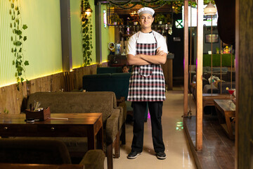 Young and confident waiter or chef standing at restaurant.