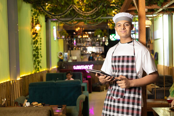Young and confident waiter standing at restaurant.