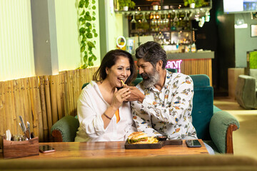 Indian Couple enjoying food and drink at restaurant.