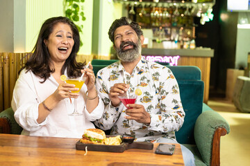 Indian Couple enjoying food and drink at restaurant