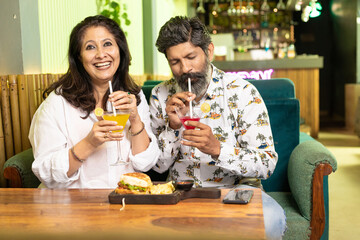 Indian Couple enjoying food and drink at restaurant