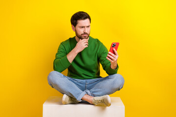 Full size photo of thoughtful young businessman touch chin decide browsing smartphone fresh news...