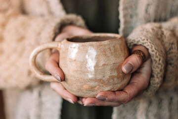 Close-up of female hands holding a handmade clay mug.Small business,entrepreneurship,creative work,hobby,leisure concept.