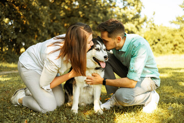 Young couple with husky dog in park on sunny day. Love concept