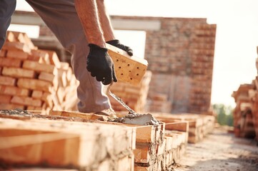 Placing the bricks. Close up view of man that is working on the construction site