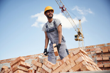 Working against blue sky. Handsome Indian man is on the construction site