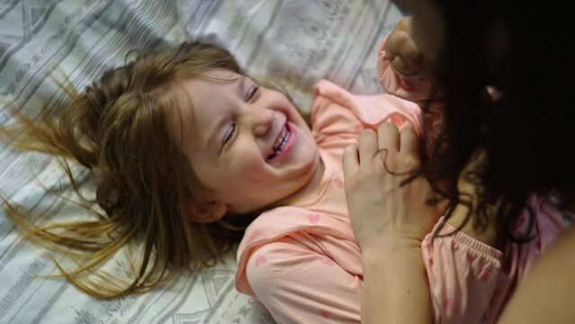 Happy childhood mother and daughter having fun on ice cream in the bedroom. Children's smiles and pranks are parental love. High quality 4k footage