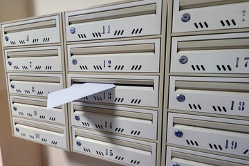 Skrzynki pocztowe w klatce schodowej domu mieszkalnego - zblizenie na list w skrzynce - obrazy, fototapety, plakaty