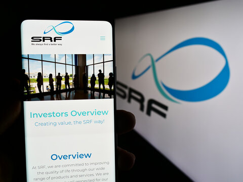 Stuttgart, Germany - 08-05-2023: Person holding cellphone with webpage of Indian chemicals company SRF Limited on screen in front of logo. Focus on center of phone display.
