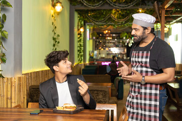 Waiter serving food to customer at restaurant