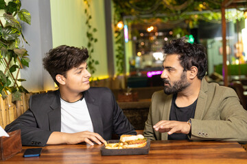 indian father discussing and guidance to his son at restaurant