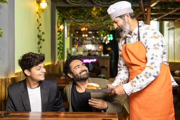 Waiter serving food to customer at restaurant