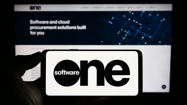 Stuttgart, Germany - 08-05-2023: Person holding cellphone with logo of Swiss software company SoftwareOne AG on screen in front of business webpage. Focus on phone display.