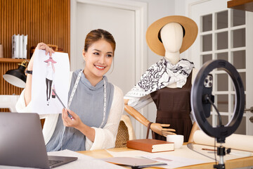 Fashion designer recording video for her blog, showing sketches to subscribers