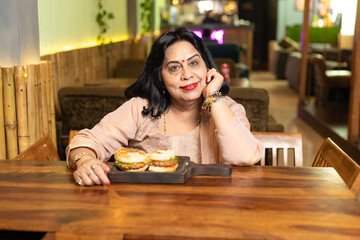 Senior woman sitting, food arrange in front of table at restaurant