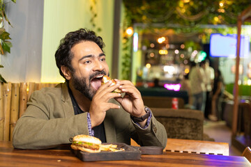 Indian man enjoying fast food at restaurant