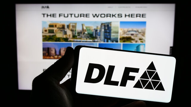 Stuttgart, Germany - 08-06-2023: Person holding smartphone with logo of Indian real estate company DLF Limited on screen in front of website. Focus on phone display.