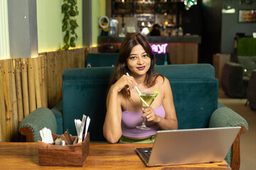 Indian Corporate woman using laptop at restaurant.