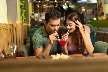 Indian Couple enjoying food and drink at restaurant.