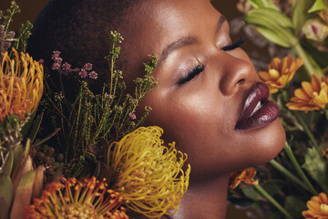 Black woman, flowers and beauty with face, makeup and natural cosmetic care isolated on studio background. African model, plants and nature with sustainable skincare, eyes closed with facial and glow