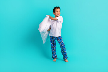 Full size photo of carefree cheerful schoolkid hands hold cushion look empty space isolated on teal...