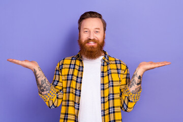 Portrait of attractive bearded guy hipster good mood hold open palms demonstrate novelty isolated purple color background