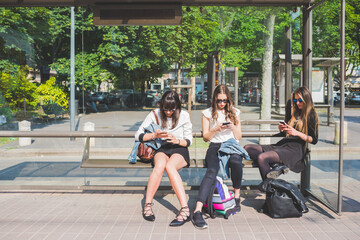 Three young women millennials outdoor in the city using smart phone