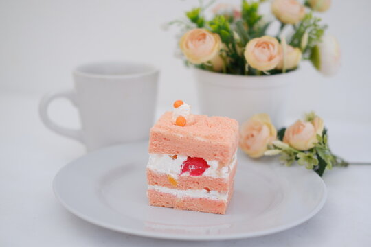 Piece of cake and cup of tea on white background, stock photo