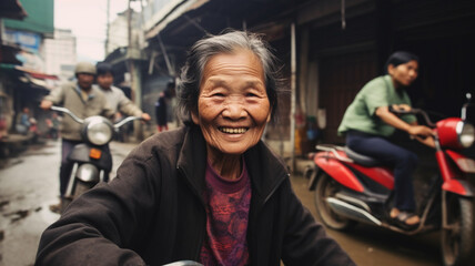 an old woman in old age sits on a scooter and drives full of fun and joy without a helmet and a thick autumn jacket through the narrow side streets of a big city, enjoying a simple life