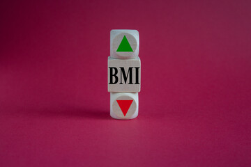 BMI big mac index symbol. Concept words BMI big mac index on wooden cube. Beautiful red background....