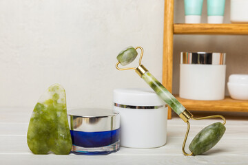 Care cosmetics on the shelf in the bathroom. Cosmetic tube. Cleanser, face and body cream, face roller and gua sha, tonic. Shelf with cosmetics in the interior of the bathroom.Beauty concept.