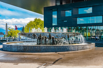 Lovely view of the famous fountain Wagenbach-Brunnen on Europaplatz with the Lucerne Culture and Congress Center in the back. The imposing fountain was built in 1934 by the architect Armin Meili. - obrazy, fototapety, plakaty