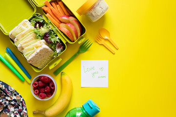 School lunch box with sandwiches, carrot sticks, apple, banana, lettuce, hummus and raspberries....