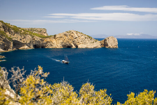 the bay gulf de la morisca with the rock gate La Foradada in sunny sky and a ship passing by