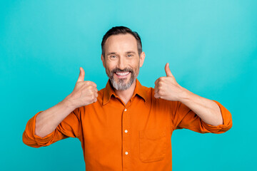 Photo of cool confident man dressed orange shirt showing two thumbs up isolated turquoise color...