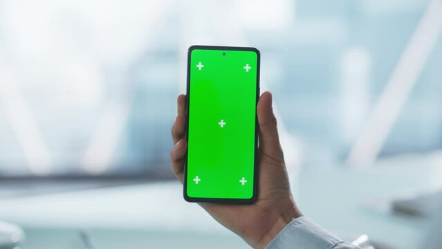 Entrepreneur Raising and Holding a Modern Phone in Front of a Camera. Smartphone with Green Screen Chroma Key Display for Use in E-Learning and Educational Tutorials, Marketing and Advertising