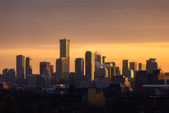 Downtown Toronto skyline at sunrise, with golden light illuminating the sky and sides of buildings