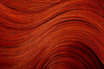 Red hair close-up as a background. Women's long orange hair. Beautifully styled wavy shiny curls....