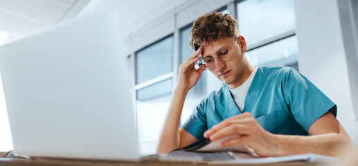 Young medical student studying for an exam in scrubs