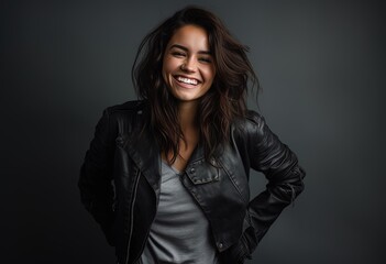 Beautiful smiling woman with a black leather jacket on a gray background