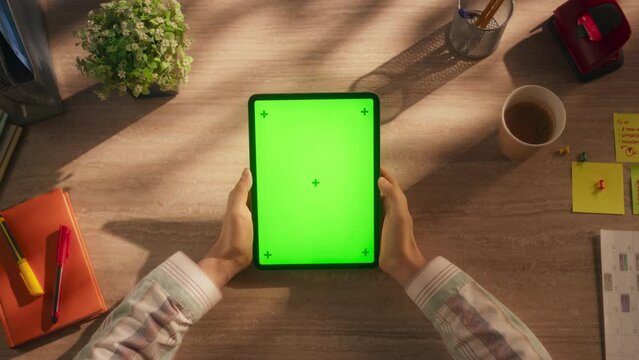 Marketing Manager Checking Social Network Posts on a Tablet Computer with Mock Up Green Screen Vertical Display. Top Down View Concept for Online Communication, Internet Branding, Business Promotions