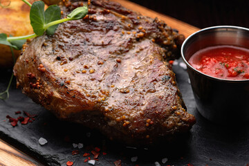 Fried meat steak on slate on a black background